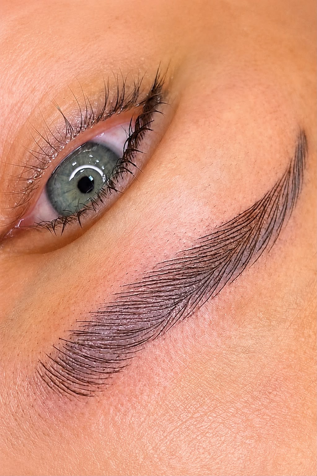 Hair-stroke microblading close up — natural feathered brow by HEADS